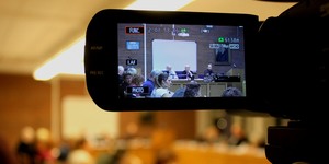 Bild på kommunfullmäktiges presidium genom kameraskärm.