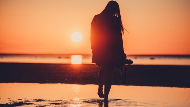 Kvinna på en strand i solnedgång